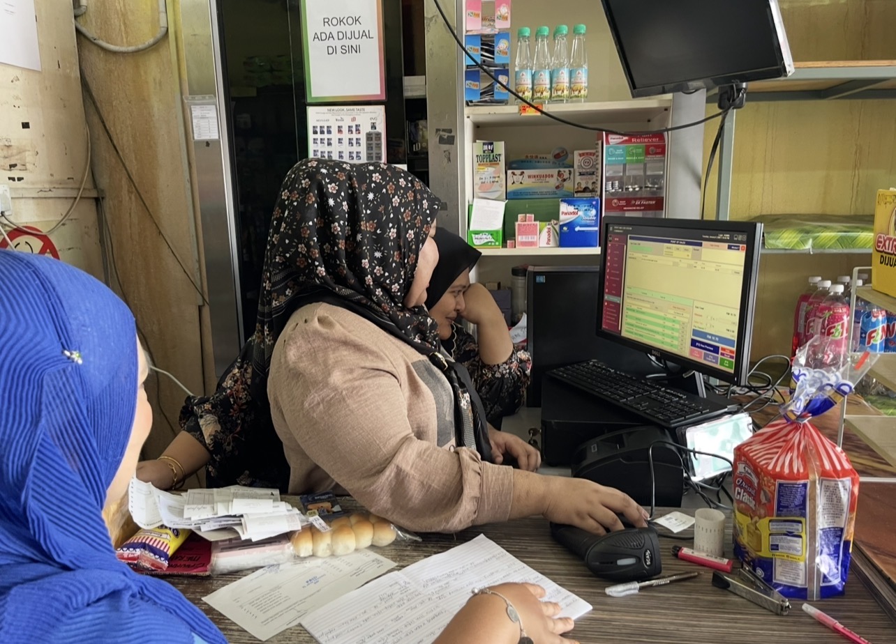 Pelanggan menggunakan sistem POS di kaunter kedai