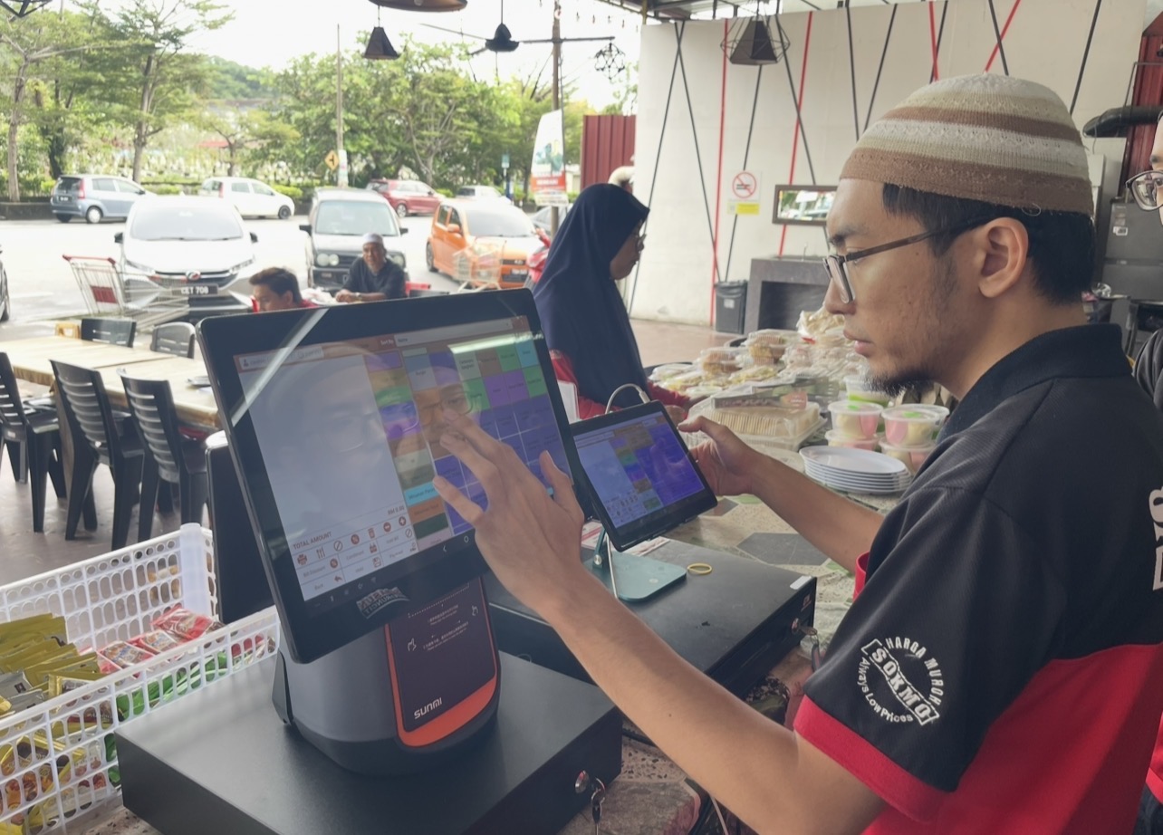 Pelanggan menggunakan terminal POS di kaunter perniagaan